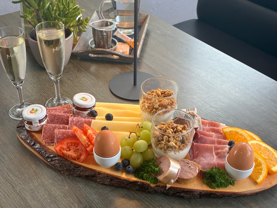Frühstücksplatte mit Brötchen, Eiern, Käse, Aufschnitt und Sekt